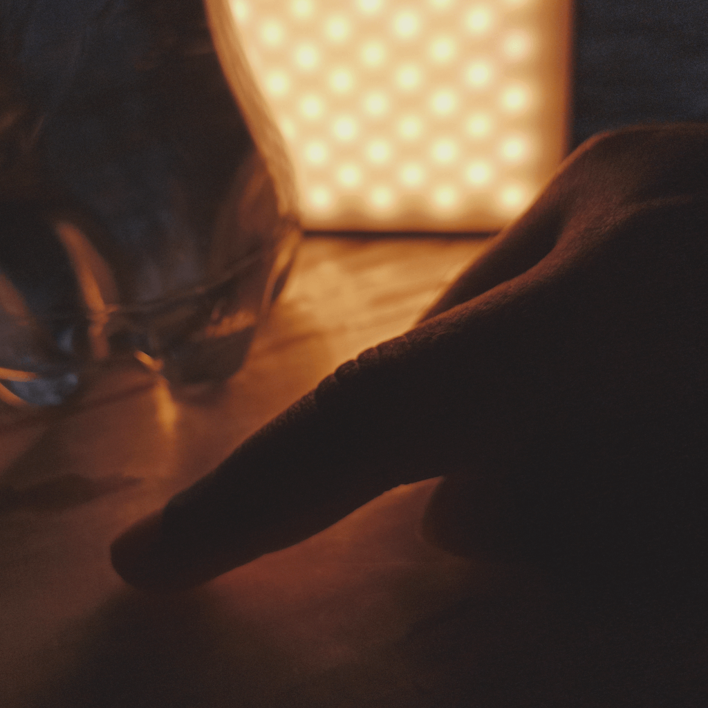 A human finger in front of a beautifully illuminated scene of water bottle.